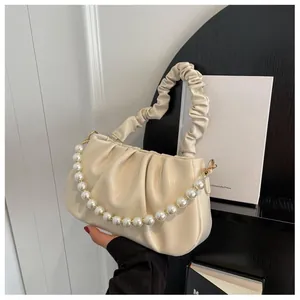 Detail of soft cream cloud bag showing pearl chain and ruched handle texture