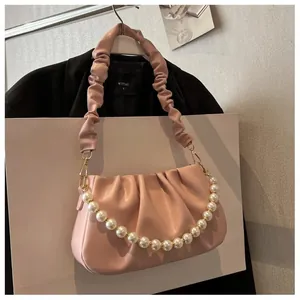 Detail of pink ruched cloud bag featuring detachable pearl chain and soft leather texture