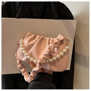 Close-up of pink ruched leather bag with elegant pearl chain and soft cloud pleat details