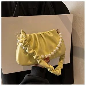 Detail of soft yellow ruched cloud bag featuring large pearl bead handle and chain strap