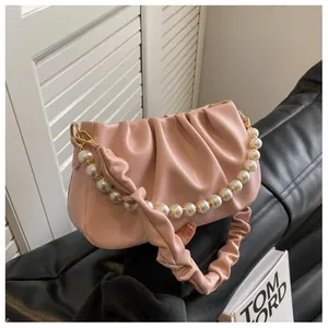 Detail of pink pleated cloud bag with elegant pearl chain and soft leather texture