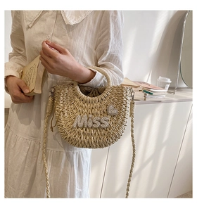 Détail du sac en paille crème avec lettrage 'MISS' en perles et ornements de cœur