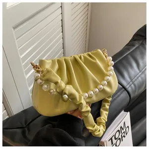 Detail of light green pleated cloud bag with pearl handle and ruffled leather strap
