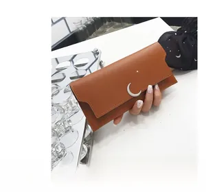 Gros plan du portefeuille long marron avec boucle métallique en forme de lune et étoile