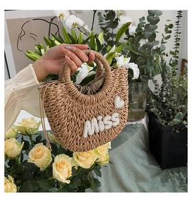 Détail d'un sac en paille tressé à la main en demi-lune avec broderie de perles 'Miss'