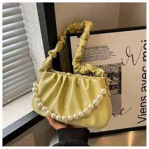 Detailed view of the yellow pleated cloud bag featuring an elegant pearl accent chain