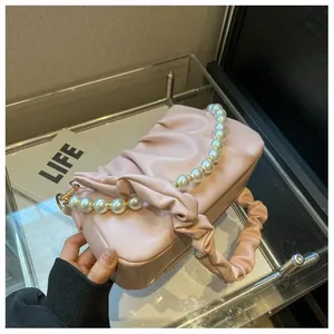 Close-up of pink pleated cloud bag featuring decorative pearl chain and soft PU leather texture