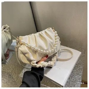 Detail of cream pleated cloud bag with elegant pearl strap and gold hardware accents