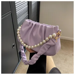 Detail of light purple ruched handbag with pearl handle and golden metal hooks