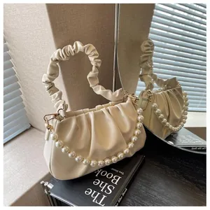 Detail of cream pleated cloud bag featuring elegant faux pearl chain and gold hardware