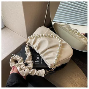 Close-up of cream pleated cloud bag with elegant pearl handle and soft leather texture