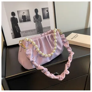 Detail of light purple pleated cloud bag with elegant pearl strap and gold metal hardware