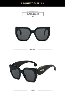 Vue détaillée de lunettes de soleil carrées noires avec logo doré sur la branche