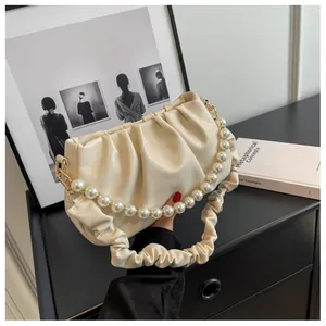 Detail of creamy white pleated cloud bag featuring premium pearl chain and soft texture