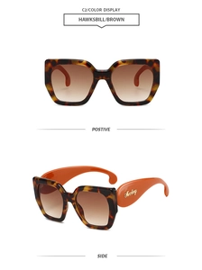 Détail de lunettes de soleil oversize écaille avec branches orange et verres dégradés marrons