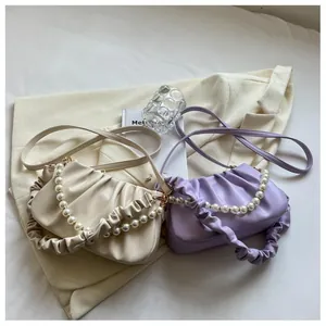 Detail of soft pleated cloud bags with pearl bead handles in cream and lavender colors