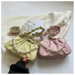 Detail of soft leather pleated dumpling bags in green and pink with pearl chain straps