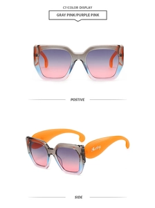 Détail de lunettes de soleil oversize avec branches orange et verres dégradés rose