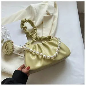 Close-up of green pleated cloud bag with elegant large pearl chain and soft leather detail