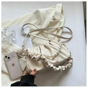 Close-up of beige ruched cloud bag with elegant oversized pearl handle and soft leather folds