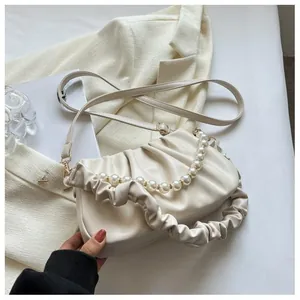 Macro detail of cream ruched cloud bag with pearl handle and soft pleated PU leather