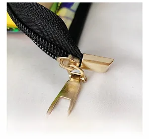 Close-up of premium gold metal zipper puller on black nylon for a PVC laser tote bag