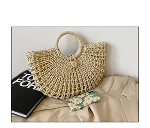 Detailed close-up of beige hollow woven straw bag with circular top handle and mesh texture