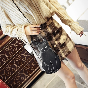 Fashionable black cat shaped crossbody bag with gold chain strap worn by a model