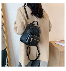 Dettaglio di un mini zaino nero trapuntato indossato da una modella in tailleur