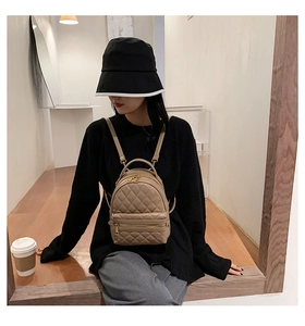 Mini zaino beige trapuntato con cerniere dorate indossato in un ambiente casual