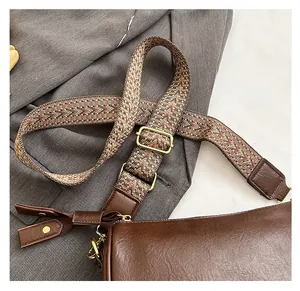 Détail du sac bandoulière en cuir marron avec large sangle géométrique et finitions dorées