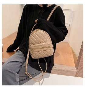 Dettaglio dello zaino trapuntato beige con doppie cerniere dorate e pelle PU morbida