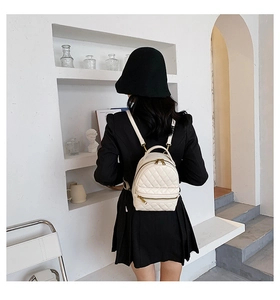 Dettaglio mini zaino trapuntato bianco con cerniere dorate indossato da modella