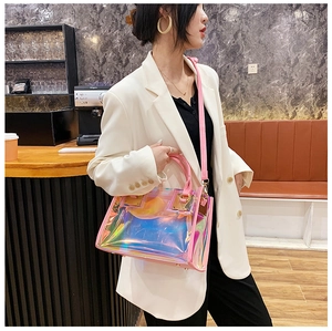 Close-up of rainbow laser PVC bag with pink trim and shiny gold metal hardware in a cafe
