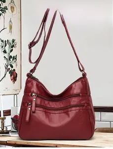 Detailed view of the dark red faux leather bag with dual zipper pockets and strap buckle