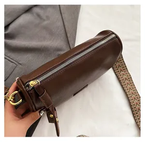 Détail d'une fermeture éclair en métal et bandoulière tissée sur un sac en PU marron