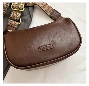 Gros plan du sac en cuir PU marron avec texture litchi et bandoulière jacquard