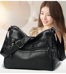 Close-up of black soft leather crossbody bag with multiple zippers and silver hardware