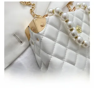 Close-up of quilted white mini bag with pearl handle and golden metal corner protectors