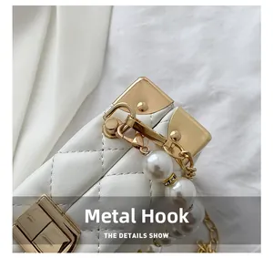 Detail of elegant gold hardware hook and quilted white texture with pearl chain