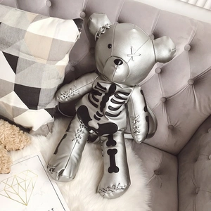 Detailed macro shot of silver bear-shaped backpack with skull bones print and stitching