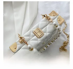 Detail shot of the gold metal clasp and white quilted leather on a crossbody bag