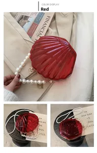 Vue détaillée du sac coquillage rouge en acrylique avec anse et bandoulière en perles