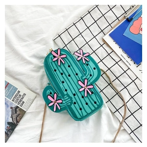Detail of green cactus shaped bag with pink flower accent and golden chain strap