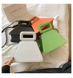 Detail of four colorful faux crocodile skin trapezoid bags with detachable shoulder straps