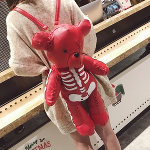 Detail of red bear-shaped leather backpack with skull print and cross-stitched arms