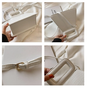 Detail of white crocodile embossed leather bag showing golden hardware and handle texture