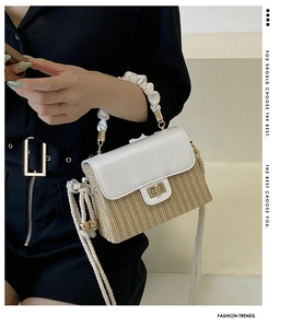 Close-up detail of the woven straw texture and white pleated handle with gold lock