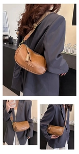 Détail d'un sac demi-lune en cuir marron avec large bandoulière tissée style rétro