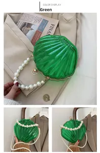 Détail du sac coquille en acrylique vert avec poignée en perles et fermoir métallique